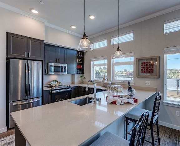 a kitchen with a large island and a stainless steel refrigerator