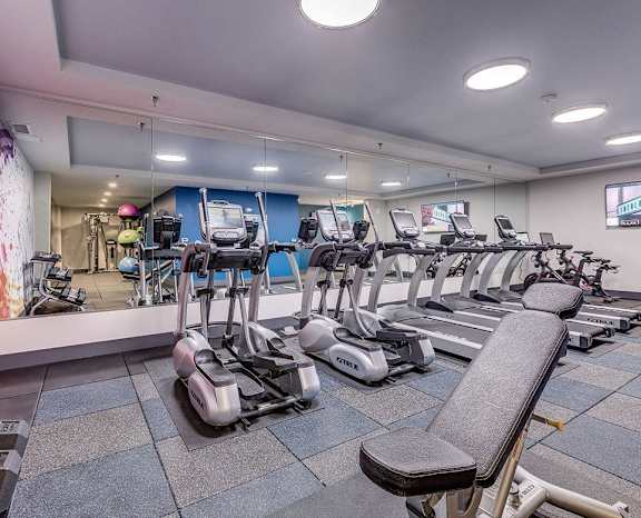 a gym with cardio machines and weights on a tile floor