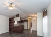 Thumbnail 13 of 18 - a living room with a ceiling fan and a kitchen in the background