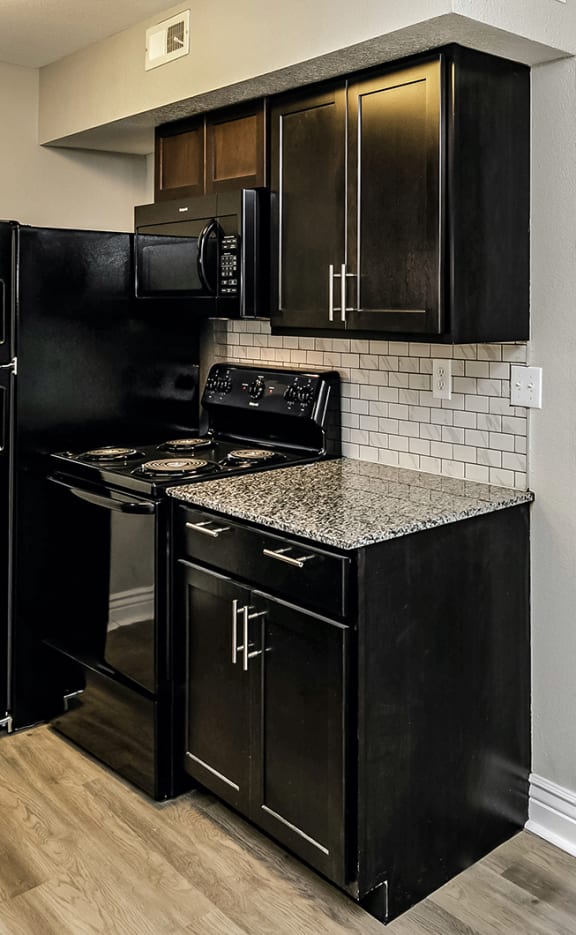 a kitchen with black cabinets and a black stove top oven