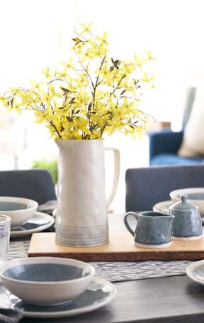 A table set for a meal with a vase of yellow flowers in the center. at The Winhall of Williams Pointe Apartments, Waukee