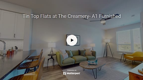 A modern living room with a caption that reads "Tin Top Flats at The Creamery- A1 Furnished".