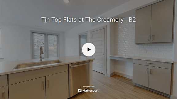 A kitchen with beige cabinets and a white brick wall.