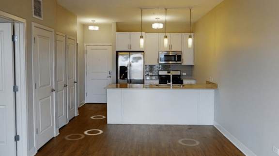 A kitchen with white cabinets and a wooden floor.
