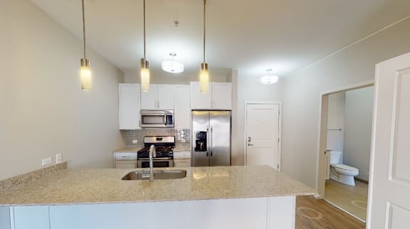 A kitchen with a granite countertop and stainless steel appliances.