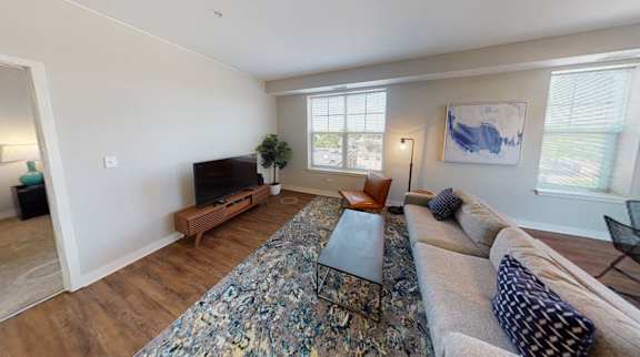A living room with a large rug and a wooden coffee table.