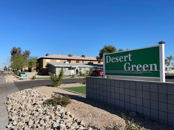 a green sign that reads desert green in front of a building
