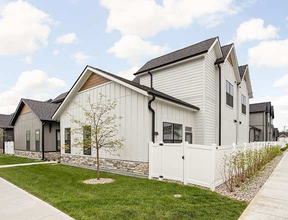 the exterior of a row of houses with a white fence  at Slate at Fishers District, Fishers, IN