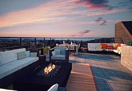A patio with a fire pit and seating area overlooking a cityscape at dusk.