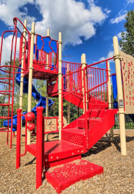a red and blue playground with trees in the background