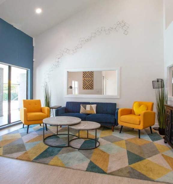 A living room with a yellow chair, blue couch, and a round table.