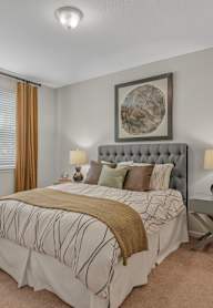 A bedroom with a large bed and a decorative plant on a table.