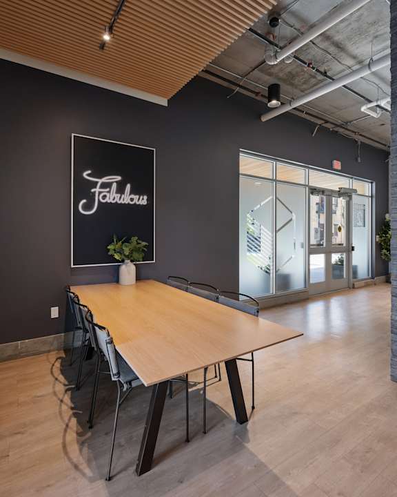 A conference room with a wooden table and chairs, a sign that says "Fabulous" and a plant on the table.