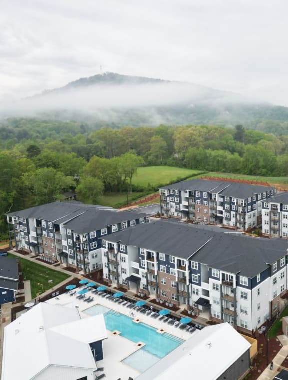 a block of apartments with a pool in the foreground and a mountain in the background