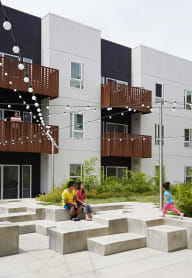people sitting on benches in front of a tall building