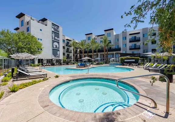 A large outdoor swimming pool surrounded by lounge chairs and umbrellas.