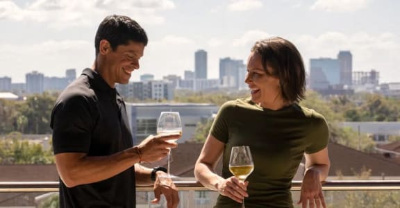 a man and woman standing on a balcony holding wine glasses