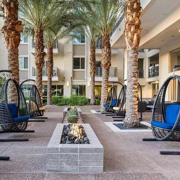 A patio with palm trees and blue chairs.