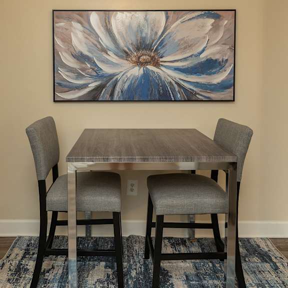 a dining table with two blue plates and a vase with a plant on it at Deer Park Apartments, Randallstown, 21133