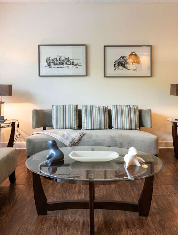 A living room with a grey couch and two framed pictures on the wall.