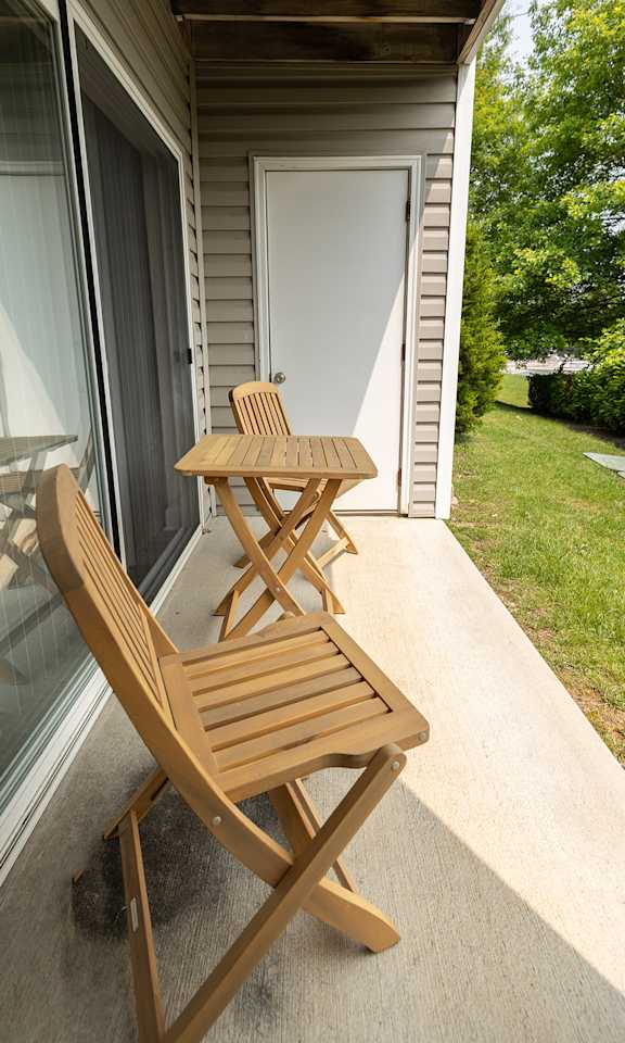 A wooden chair and table are on a patio.