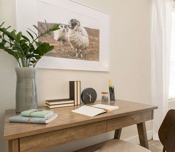 a desk with a vase and a picture of birds on the wall above it