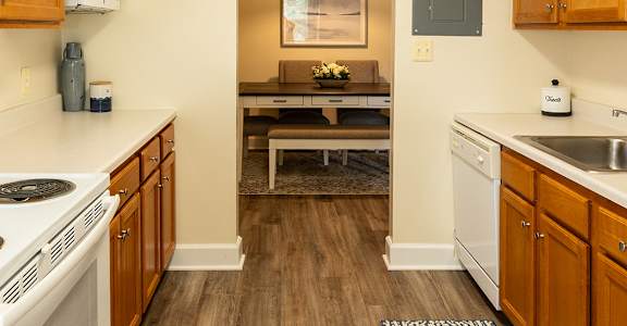 a kitchen with white appliances and wooden cabinets and a rug