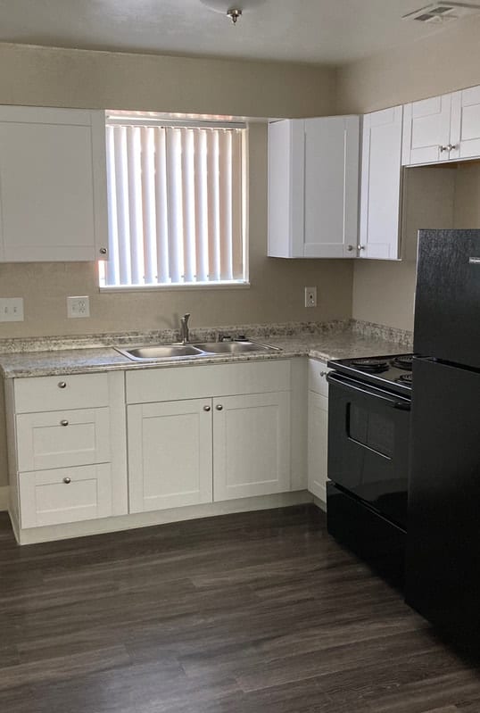 a kitchen and living room with white cabinets and wood floors