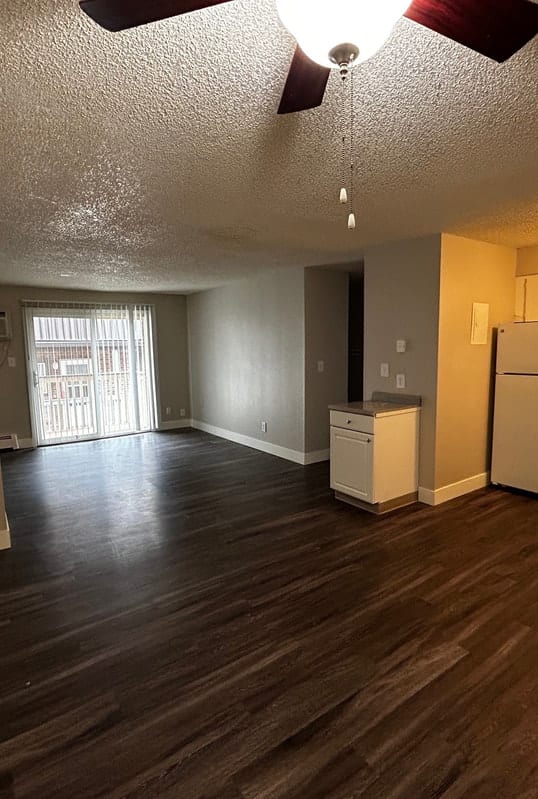 a kitchen and living room with white cabinets and wood floors
