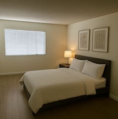 A bedroom with a large bed and two framed pictures on the wall.