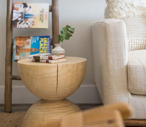 a living room with a chair and a table with a book shelf in the background