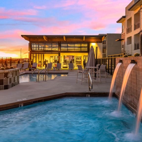 a pool with two fountains and a building in the background