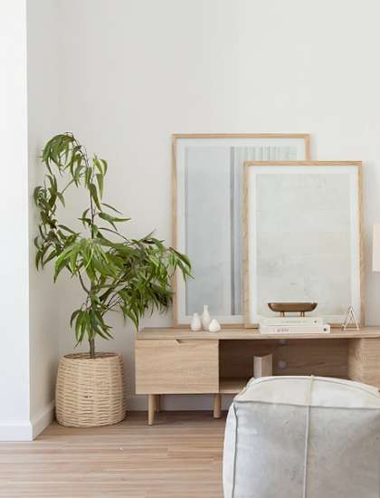 A living room with a white couch, a wooden table, a mirror, a plant, and a lamp.