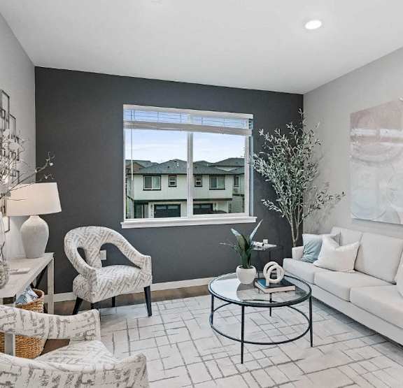 A living room with a white couch, a black coffee table, and a large window.