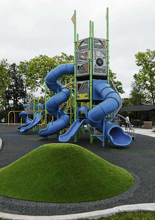 A playground with a blue slide and a green hill.