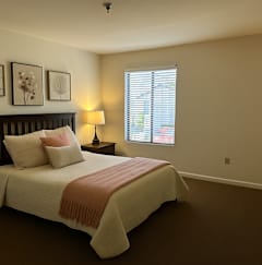 A bedroom with a bed, nightstand, and window.
