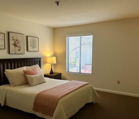 A bedroom with a bed, nightstand, and window.