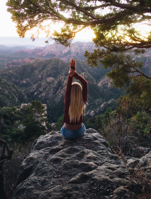 Woman Sitting on Rock Stretching and Admiring Mountain Views