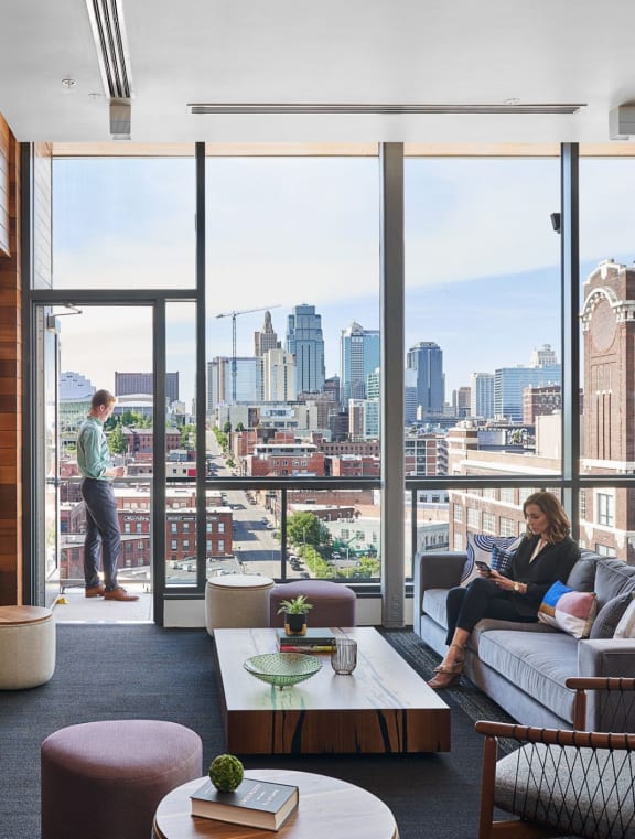 a woman sits on a couch in a living room with a view of the city in the