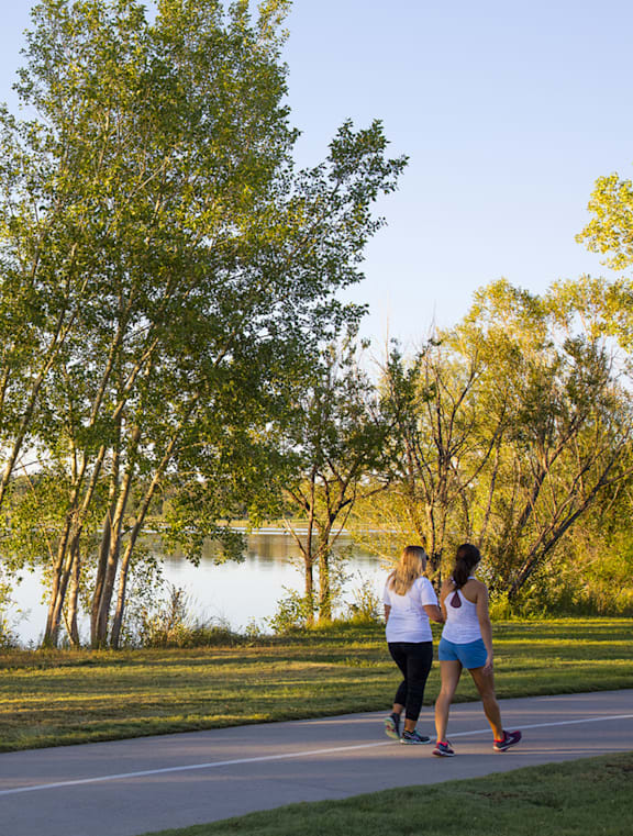 Two women jogging on a path near a lake.