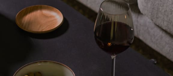 a glass of red wine on a table with a bowl and a bowl of cereal