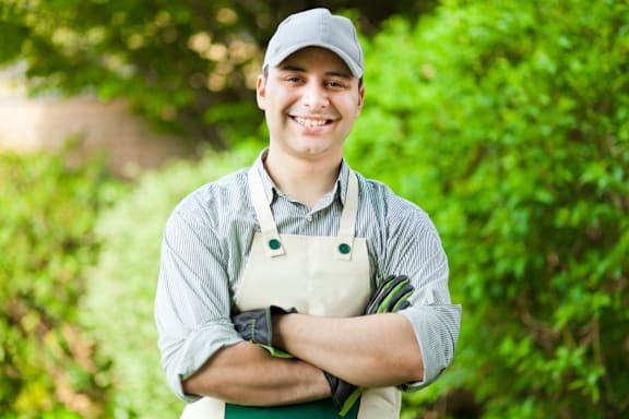 A man wearing a cap and apron standing with his arms crossed.