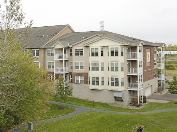 a large apartment building with balconies and a grassy area in front of it