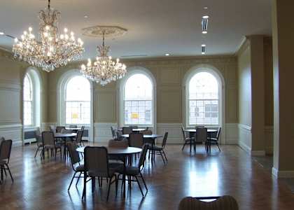 A large room with tables and chairs and a chandelier.