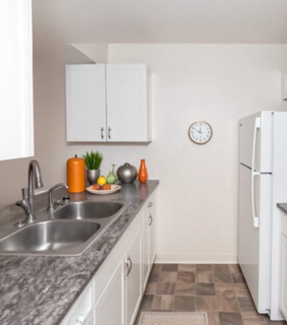 A kitchen with white cabinets and a clock on the wall.