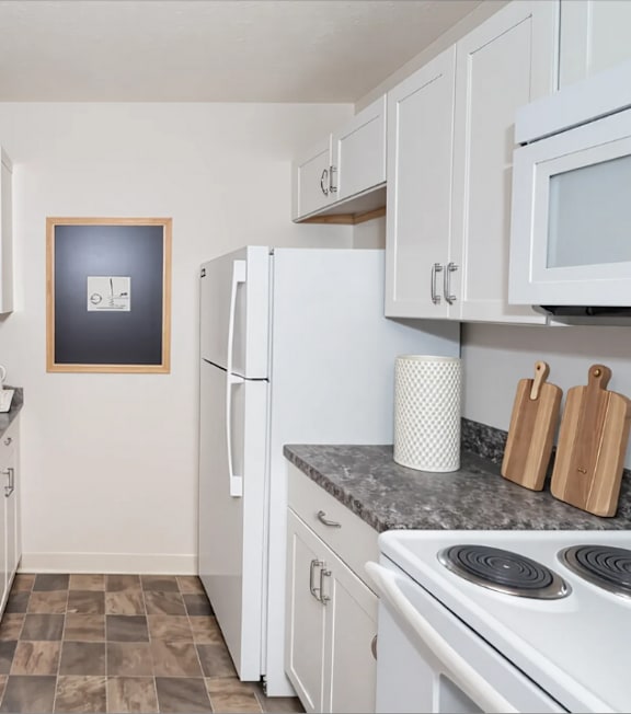 A kitchen with white cabinets and a fridge.