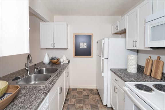 A kitchen with white cabinets and a fridge.
