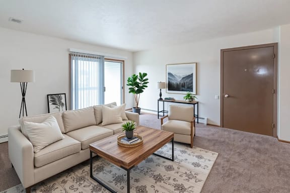 A living room with a couch, chair, and potted plant.