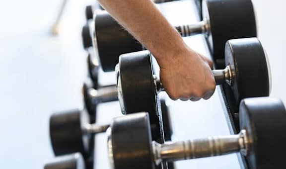 A person's hand is lifting a dumbbell from a rack.