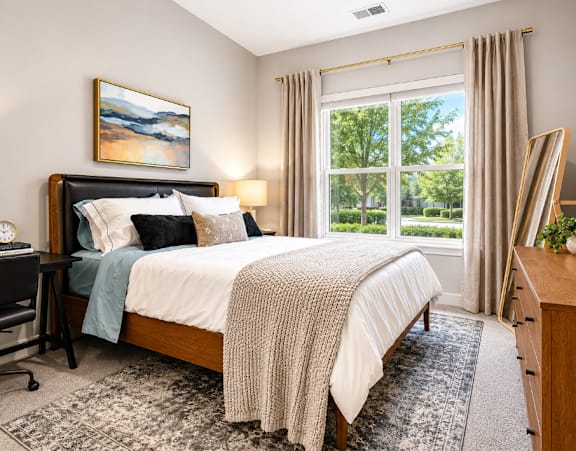 A bedroom with a large bed, a desk, and a chair.